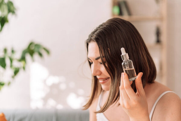 Lady holding glass bottle with pipette in her hand.