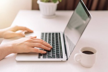 Lady typing on a laptop at the table.