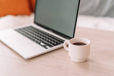 Laptop with white cup of coffee on the table.