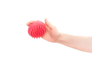 Massager for the scalp in pink color in female hand against white background.