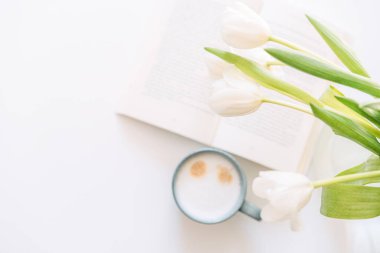 Vazoda bir buket lale ve beyaz arka planda bir fincan kahve..