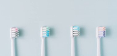 Mavi arkaplandaki elektrikli diş fırçasından dört tane çok renkli başlık..