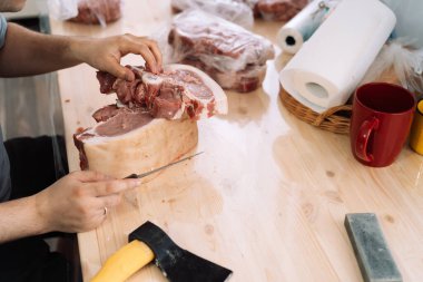 Tahta bir masada pirzola parçalarını keserek..