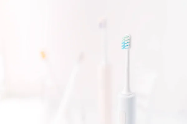 Childrens toothbrushes in glass cup and electric toothbrushes against white background.