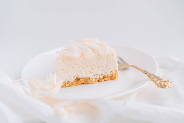 Beyaz arka planda çatallı, hindistan cevizi aromalı beyaz peynirli kek..