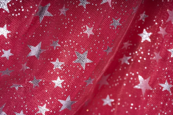 Transparent tulle background with glittering stars on red tulle.