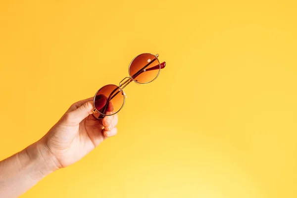 stock image Round sunglasses in hand against yellow background.