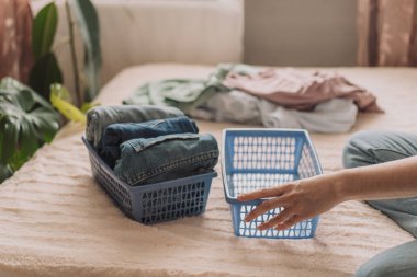 Kadın kotunu mavi bir konteynıra katlıyor..