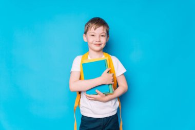 Sarı bir sırt çantası ve mavi arka planda bir kitabı olan bir öğrenci..