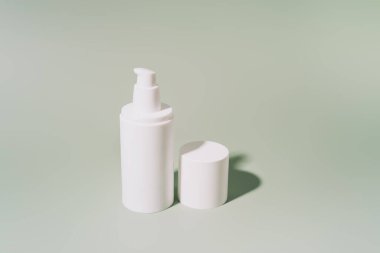 Kozmetik için beyaz tüp ile yeşil arka planda sert ışık altında.