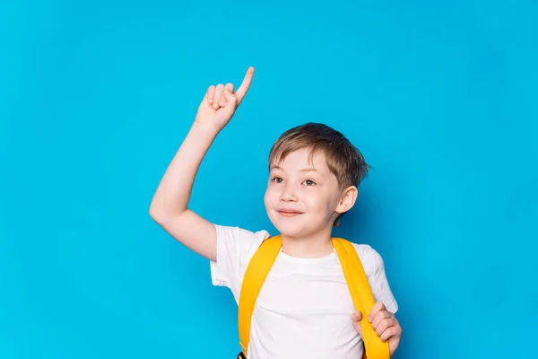 Αγόρι Κίτρινο Σακίδιο Σήκωσε Χέρι Του Πάνω Μπλε Φόντο — Φωτογραφία Αρχείου