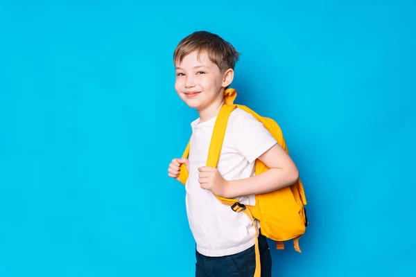 Schoolboy Κίτρινο Σακίδιο Στέκεται Πλάγια Μπλε Φόντο — Φωτογραφία Αρχείου
