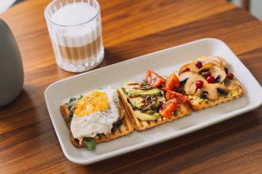 Kahvaltıda farklı malzemelerle tost ve bir fincan kahve..