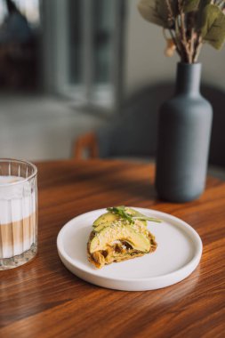 Kahveli beyaz tabakta avokado tostu..