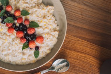 Ahududulu yulaf ezmesi ve beyaz bir fincanda kuşüzümü ve kaşık..