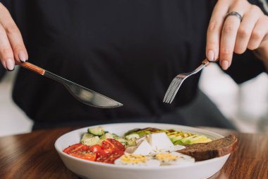 Kız peynirli, yumurtalı ve çavdar ekmekli sebze salatası yiyor..