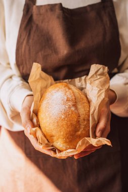 Tahta bir masada, buğday ve balkabağı kulaklı taze ekmek..