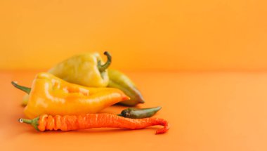 Turuncu arka planda tatlı ve acı biber.