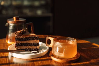 Beyaz bir tabakta, beyaz bir tabakta, güneş ışığının altında çay olan bir pastanın içinden bir fıstık parçası..