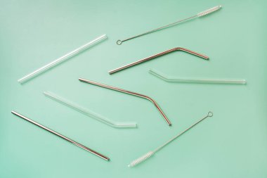 Metal ve cam yeniden kullanılabilir pipetler ve yeşil arkaplanda fırçalar.