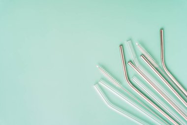 Metal ve cam yeniden kullanılabilir pipetler ve yeşil arkaplanda yakın plan fırçalar.