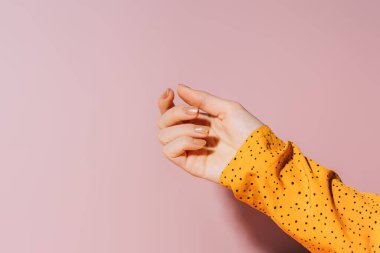 Pembe arka plan ve maniküre karşı altın renkli tırnakları olan boş bir kadın eli..