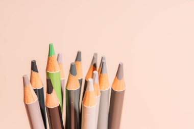 Oil pencils under hard light against a beige background.