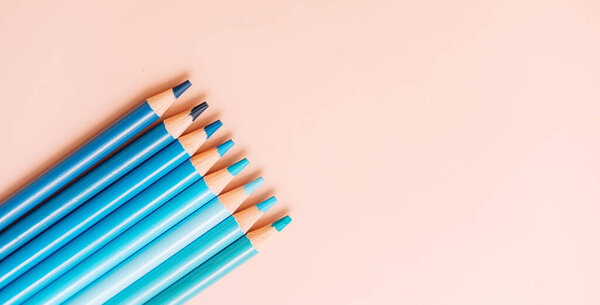 Blue pencils lie in a row on a beige background.