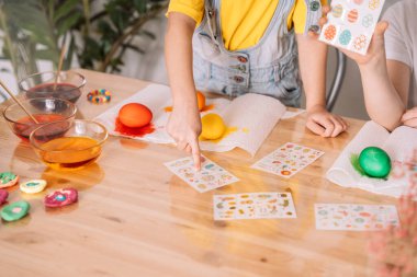 Çocuklar farklı renklerde yumurta boyayıp çıkartma yapıştırarak Paskalya için hazırlanıyorlar..