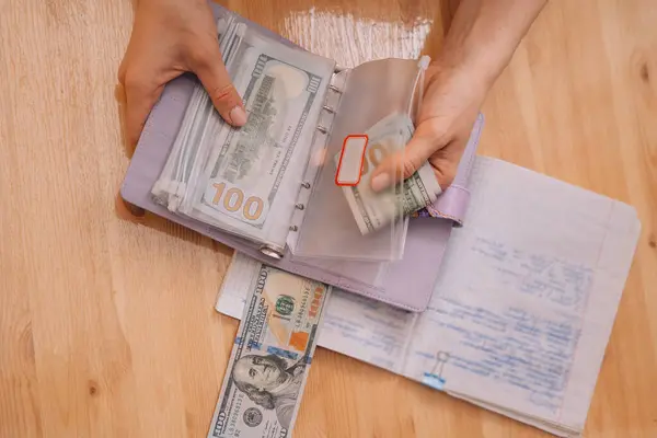Putting money into different zip bags in a notepad.