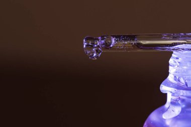 Bir damla serum pipetten mavi bir kavanoza akar. Yüksek kalite fotoğraf
