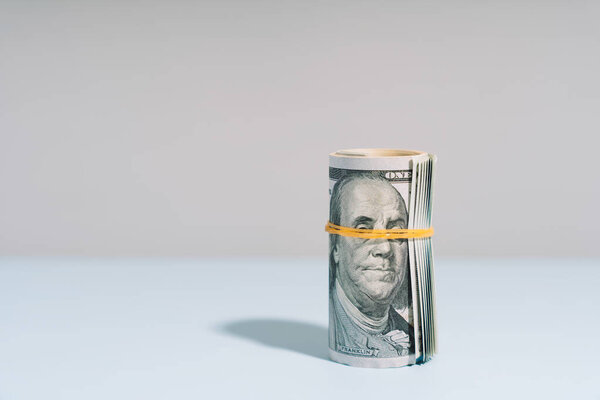 One hundred dollar bills rolled up on light background. High quality photo