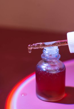 Deri bakım serumu kırmızı ışık altındaki bir pipetten akar. Yüksek kalite fotoğraf