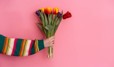 Bir buket çiçeği pembe arka planda tutan kadınların yan görüntüsü.