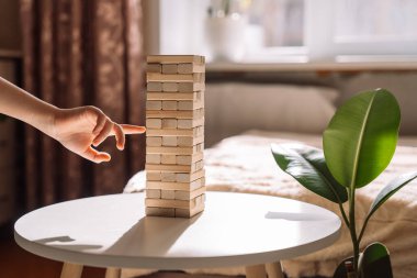 Çocuk Jenga oyununun tahta bloğunu kaydırıyor.