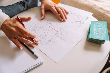 Bir astrolog natal çizelgeye kalemle çizer..