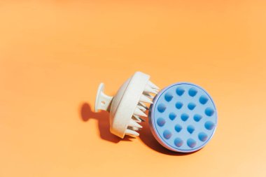 Blue and white massager for the scalp on a yellow background.