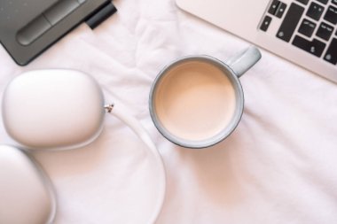 Kablosuz kulaklıkları ve bir fincan kahve ve grafik tableti olan rahat bir iş yeri..