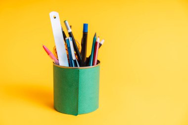 Sarı arka planda kırtasiye malzemesi ile yeşil kağıtta teneke kutu.