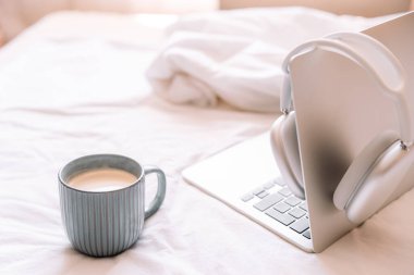 Laptopta kablosuz kulaklıklar ve bir fincan kahve asılı rahat bir iş yeri..