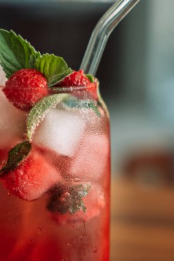 Böğürtlenli limonata, cam bardakta buz ve ahşap bir masada pipet..