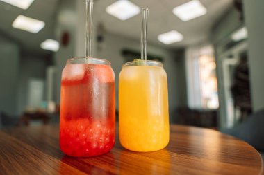 Böğürtlenli limonata, cam bardakta buz ve ahşap masada saman..