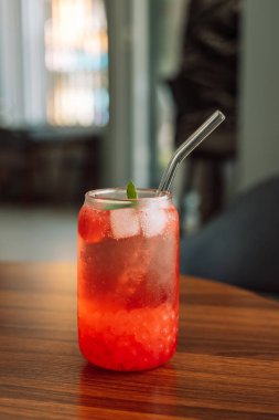 Böğürtlenli limonata, cam bardakta buz ve ahşap masada saman..