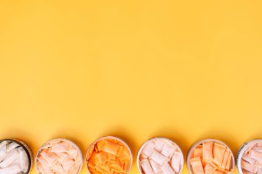 Farklı aromalı çok renkli çantalar sarı arka planda kavanozlar halinde dizilir..