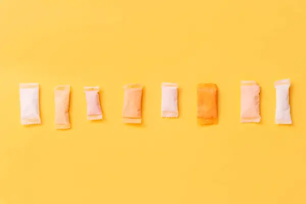 stock image Multi-colored and different-flavored snus bags are laid out in a row on a yellow background.