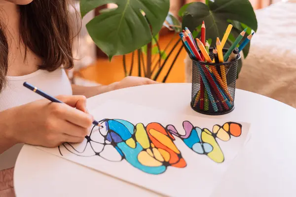 Bayan beyaz bir çarşafa renkli kalemlerle resim yapıyor..