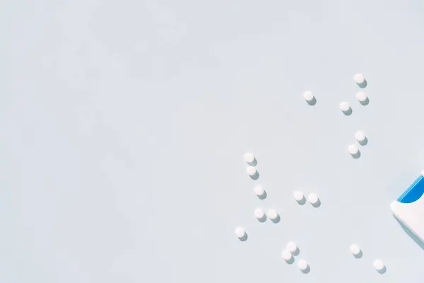 stock image Scattered sweeteners in the form of tablets next to packaging on a blue background.