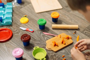 Bir çocuk şefçilik oynar ve plastik tabakları hazırlar..