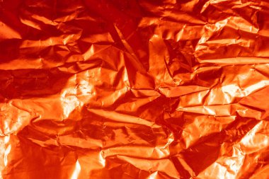 Kırmızı ve buruşuk folyonun ışık altında arkaplanı.