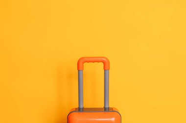 Sarı arka planda turuncu bavul.